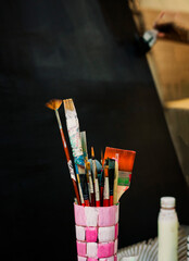 Vibrant Artist Paintbrushes in Pink Holder Against Dark Background