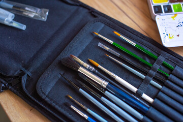 Independent Artist Day. Artist's Paintbrush Set with Watercolors on Wooden Table