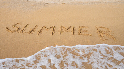 Summer beach scene with ocean waves washing over sandy shoreline