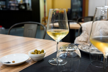 Elegant dining with white wine and olives on a wooden table in a cozy restaurant setting