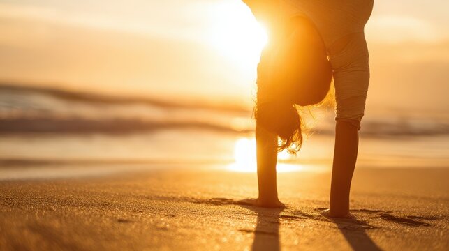 Person in a handstand pose on a beach at sunset.