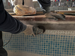 person working in a swimming pool with a small radial saw