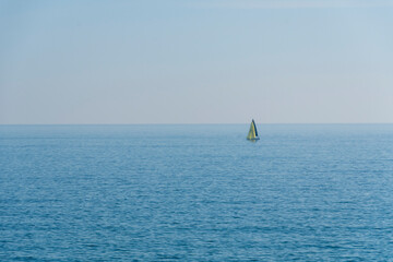 sailboat sailing alone in a calm sea with the horizon in the background