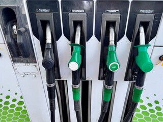 Fuel pump nozzles at a gas station, displaying options for refueling vehicles with gasoline or...