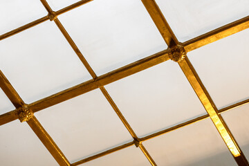 Horizontal view of a golden grid structure on a ceiling light portal