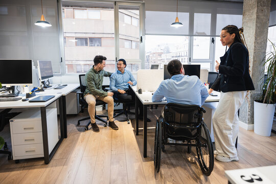 Diverse team working together in a bright, modern office, showcasing collaboration, inclusion, and the integration of disabled individuals into the workplace
