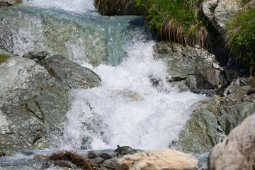 Scenic view of stream with rocks and splashing water at Lötschental Valley in the Swiss Alps on a...
