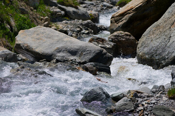 Scenic view of stream with rocks and splashing water at Lötschental Valley in the Swiss Alps on a...
