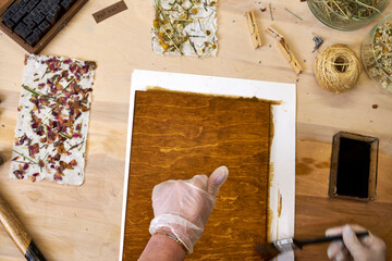 Brushing wood panel for decorative craft with handmade floral paper. Eco-friendly art project using...