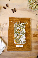 Final craft result: handmade floral paper mounted on stained wood board, surrounded by tools and...