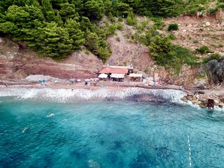 A drone photo from the sea onto a small bar and the beach in Sveti Stefan Montenegro