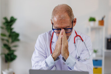 Worried male doctor working on computer at he desk.doctor, worried,stress, tired, laptop, black,...