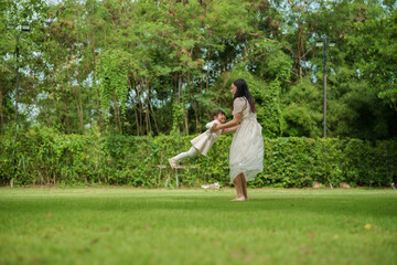 mother and toddler girl playing circling around on grass field at park
