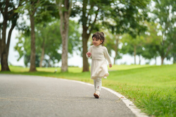 Fototapeta premium happy toddler girl walk along a pathway in park