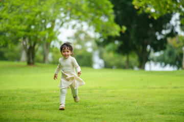 happy toddle girl in white dress running on green grass field