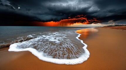 Vibrant sunset over a sandy beach with dark storm clouds and gentle ocean waves
