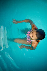 Teen girl enjoys summer in the pool, showcasing joy while relaxing in the water with a big smile