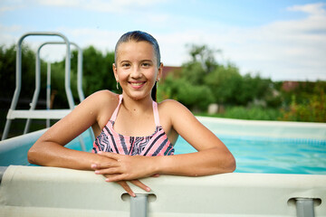Teen girl enjoying a summer day by the pool with a cheerful smile and relaxed demeanor in a sunny outdoor setting