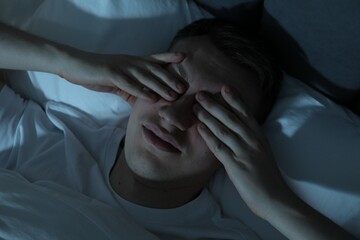 Frustrated man suffering from insomnia in bed indoors, top view