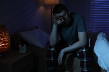 Frustrated man suffering from insomnia on bed indoors