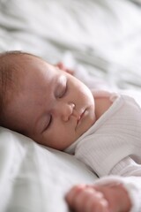 Cute newborn baby sleeping on bed, closeup