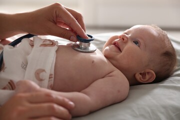 Pediatrician examining baby with stethoscope at table in clinic, closeup