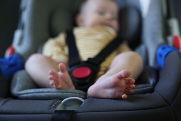 Cute little baby fastened in car seat, selective focus