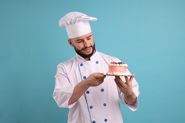 Happy confectioner in uniform holding delicious cake with berries on light blue background