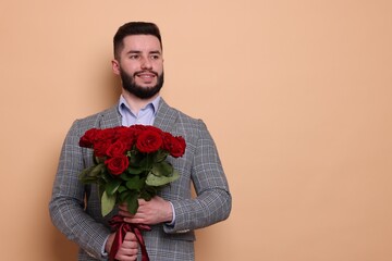 Happy man with bouquet of red roses on beige background, space for text