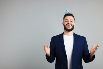 Happy Birthday. Handsome man with party hat on grey background, space for text