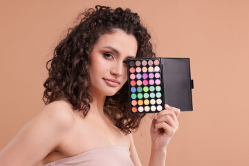 Woman with eyeshadow palette on beige background