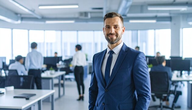 A successful businessman is looking directly at the camera in a professional office setting.