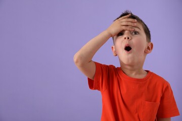 Portrait of surprised boy on purple background, space for text