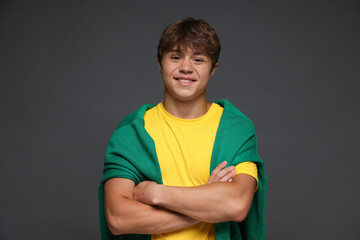 Portrait of smiling teenage boy with crossed arms on grey background