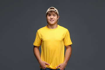 Portrait of smiling teenage boy in baseball hat on grey background