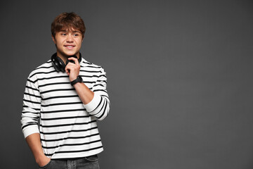 Smiling teenage boy with headphones on grey background. Space for text