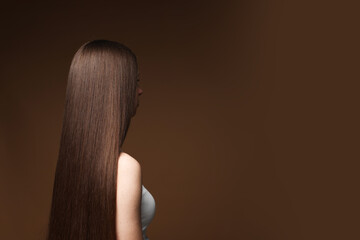 Teenage girl with healthy long hair on brown background. Space for text