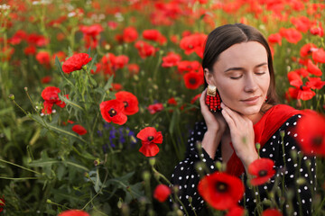 Beautiful woman among red poppy flowers in wildflower meadow