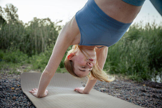woman doing yoga pose upside down on mat outdoors