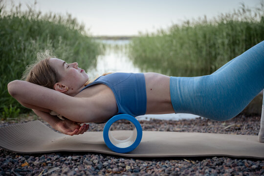 woman lying on foam roller for back massage on outdoor summer workout