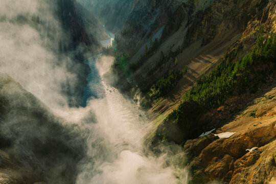 Steam and mist swirl around a dramatic canyon waterfall.
