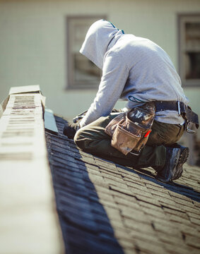 Roofer with a drill fixes a roof in a residential area