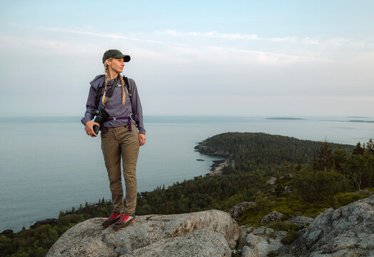 One female hiker looks at ocean view, Acadia National Park, Maine