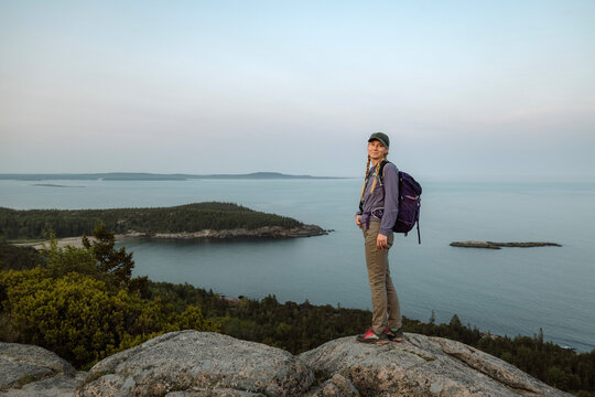 Female hiker stands on mountain with view, Acadia National Park, Maine