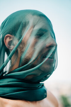 Close-up of man's face wrapped in flowing green translucent fabric