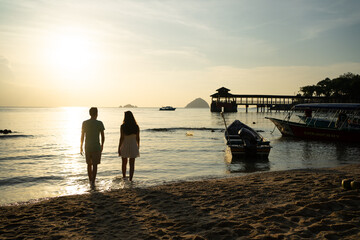 Tourists enjoying golden sunset on tropical beach in mabul island, malaysia