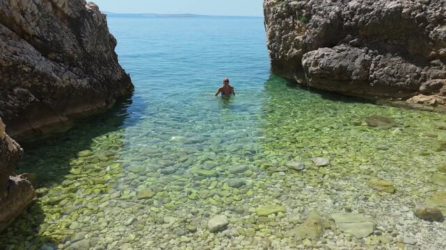 Beautiful Young Woman in Bikini Swims in Stara Baska Beach Krk Island, Croatia. Mediterranean Summer. Aerial Shot From Above. Blue Sea the Rocks Mountains and Coastline Calm Sea With Clear Blue Water
