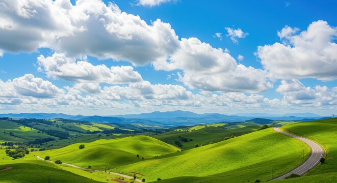 A scenic view of rolling green hills with a winding road under a cloudy sky