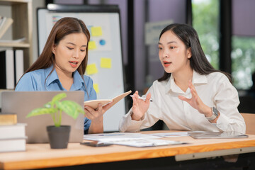 Two Asian businesswomen are having a meeting and discussing their work.	