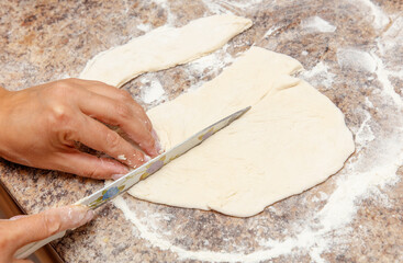 A person is cutting a piece of dough with a knife